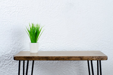 Green flowerpot in a white pot on a wooden table. Desktop.