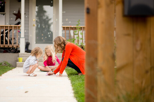 Mother and daughters draw with chalk