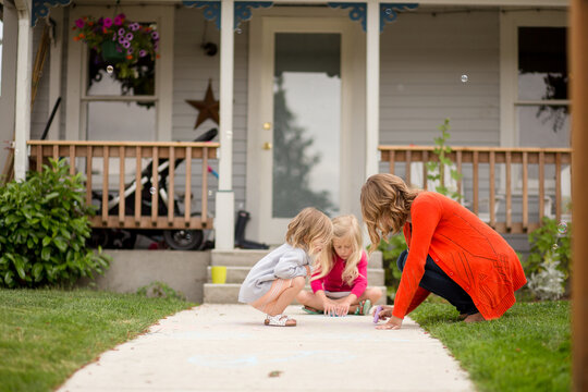 Mother draws with chalk on front walk