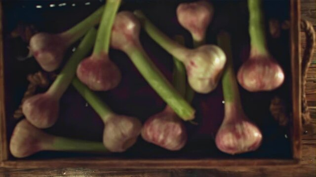 Super slow motion tray with garlic falls on a wooden table. Filmed on a high-speed camera at 1000 fps. High quality FullHD footage