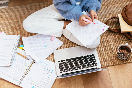 Crop student doing homework on floor