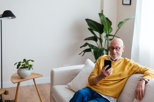 Relaxed Aged Man Browsing Smartphone At Home