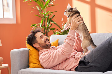 Smiling man playing with cute dog at home