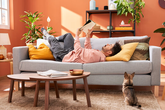 Male owner reading book near dog