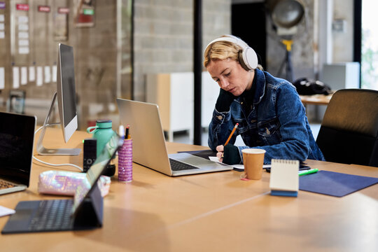 Girl in headphones taking notes.