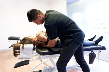 Ethnic chiropractor stretching back of woman