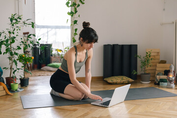 Young woman having online yoga class at home 