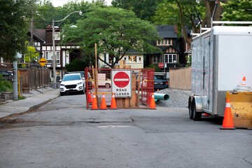 Road Closed, men at work signage:  Pipes and fixtures used in a project to replace and upgrade...