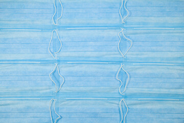 Twelve blue medical protective masks with rubber bands. Arranged on the surface in rows. Texture and background.