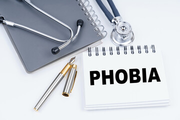 On the table are a stethoscope, a pen and a notebook with the inscription - Phobia