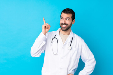 Young caucasian man over isolated background wearing a doctor gown and pointing up