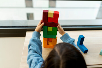 little girl playing with wooden blocks at home