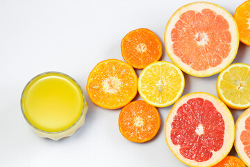 Sliced citrus on a white background with a glass of fresh juice. Grapefruit, lemon, tangerine.