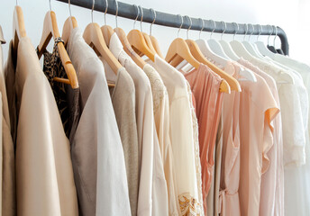 Stylish womans clothes hanging on a rack natural colors, trending concept,pastel colors in white...