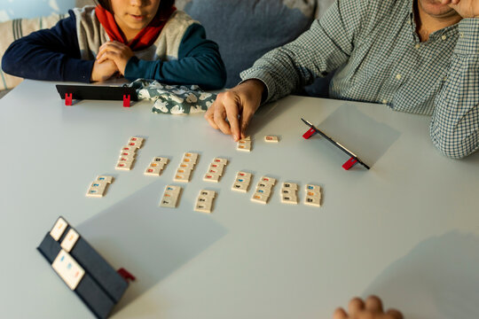 father and sons playing rummy on table at home