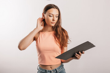 Girl student writes information. Beautiful young business woman isolated on gray background. Achieving career wealth business concept. Mockup copy space. Hold a clipboard with documents