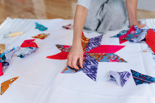 A woman is sewing patchwork in a home workshop.