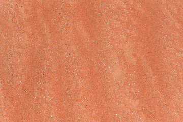 Waves of red sand. Close up of white red sand. The sand on the beach in red tones. Background with red sand in the desert.