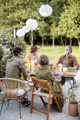 Group of friends wearing face mask during a lunch outdoors, having a serious conversation, spending time together during a pandemic