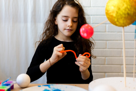 Little girl doing saturn's ring out of modeling clay