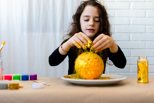 Girl putting golden glitter at solar system science project