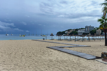 wooden walkway on the beach against the background of the sea with yachts and cloudy sky