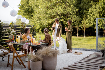 A group of young friends having great summertime, dining and talking at backyard of the country...