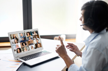 Intelligent clever indian male office employee making video call, talking ia video connect on the laptop, eastern man in smart casual shirt holding negotiation, discussion with group of diverse people