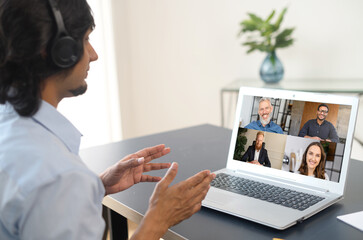Fototapeta na wymiar Indian male freelancer talking online with group of diverse colleagues or classmates, man participates in video conference with multiracial team, virtual meeting on the laptop, e-learning