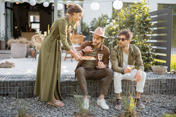 Group of young friends spending summertime together, having snacks on a porch of the country house outdoors