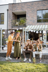 Group of young friends spending summertime together, having snacks on a porch of the country house outdoors