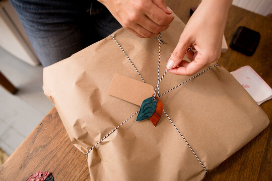 Woman ties twine and leather leaves on package
