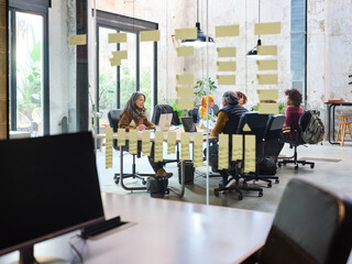 Coworkers behind glass wall with Kanban board