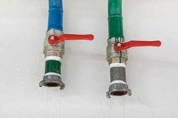 Two water tap with red valve handle inside building, at home. Fire safety equipment.