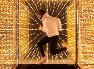 Black man jumping in mirror labyrinth