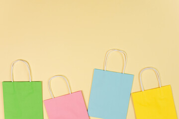 Colorful paper shopping bags on yellow background top view. Summer sale concept.