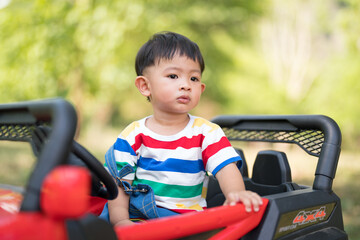 Asian Little boy sitting on a toy car and looking
