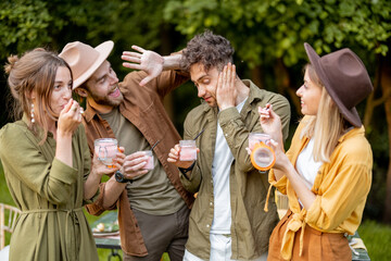 Group of young friends having fun together eating ice cream in glass jars during a festive snack...