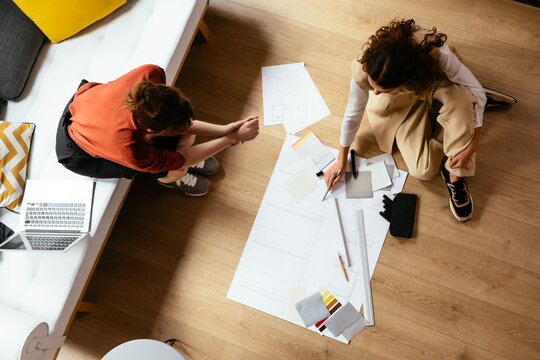 Female architects working on blueprint on floor
