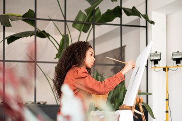 Mixed race Woman painting a picture at her studio.