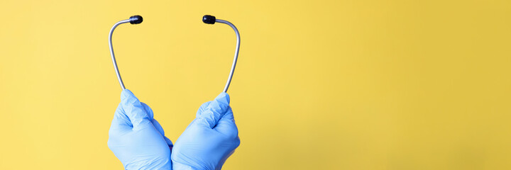 Doctor's hands in gloves hold stethoscope closeup