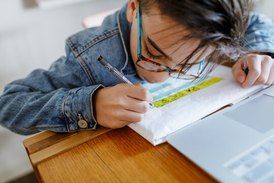 Boy writing on wrapper paper "for dad" in Spanish on a gift 