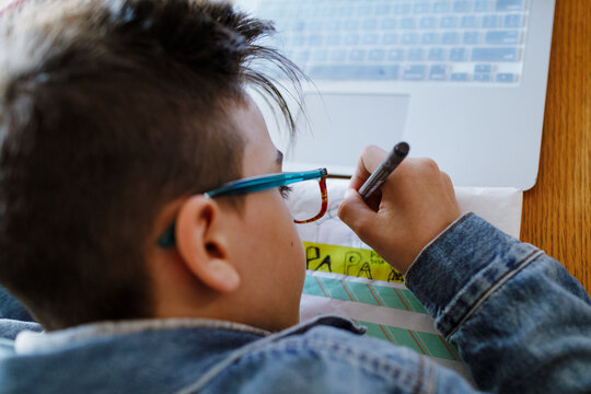 Boy writing on wrapper paper "for dad" in Spanish on a gift 
