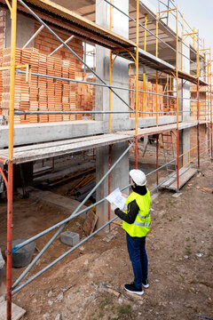 Engineer with blueprint inspecting construction site