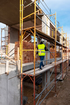 Builder walking on scaffolding on construction site