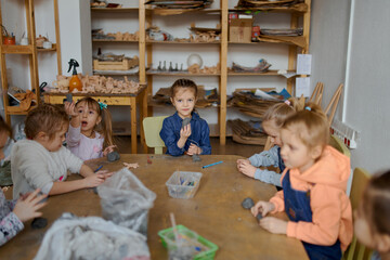 group of 5 year old preschool children in an art school learn to sculpt from clay