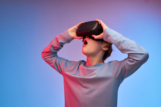 Surprised Teen Boy Wearing Virtual Reality Goggles Watching Movies Or Playing Video Games,looking Up At Copy Space. Side View Portrait Of Excited Teen Boy In Goggles Glasses For Virtual Reality Game