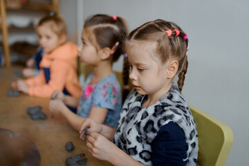 group of 5 year old preschool children in an art school learn to sculpt from clay
