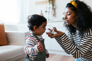Indian mother giving water to baby