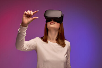 VR technologies. Confident young woman in virtual reality headset pointing in the air while...